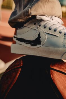 Close-up of a sneaker on a basketball, showcasing modern street fashion style.