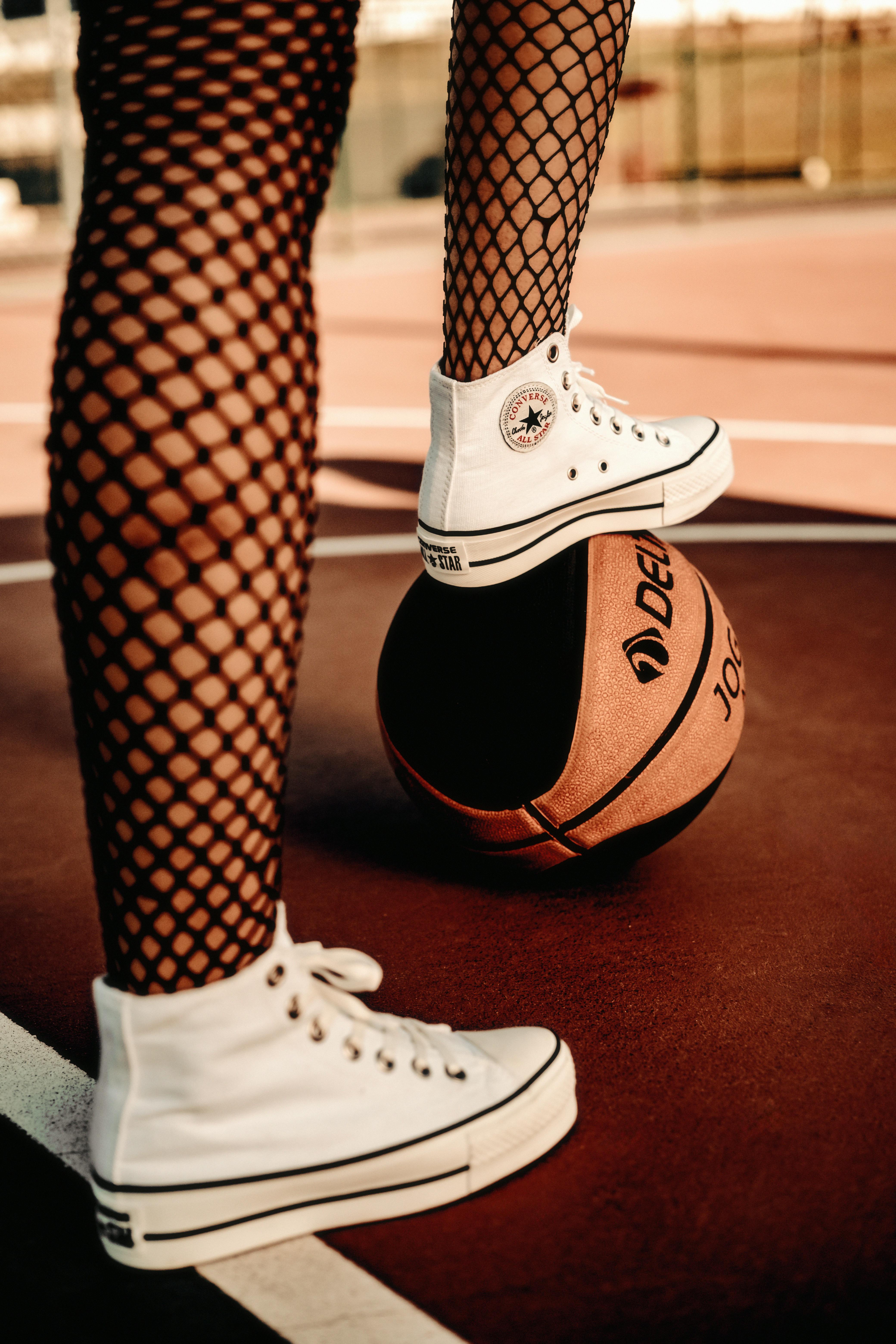 woman legs in tights standing on basketball ball