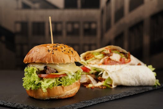 Close-up of a cheeseburger and shawarma wrap on a slate plate. Classic fast food combo.