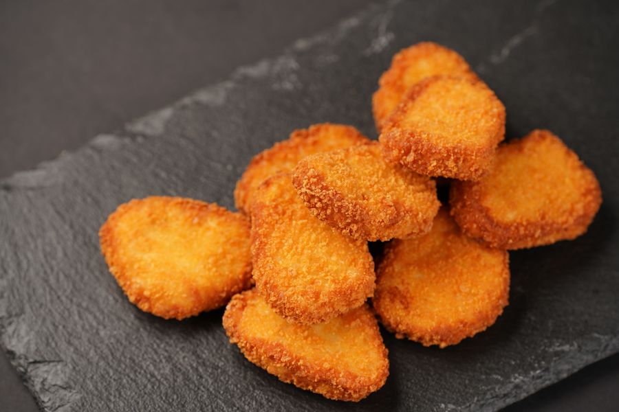 Golden breaded chicken nuggets stacked on a slate plate — photo by Vilnis Husko on Pexels