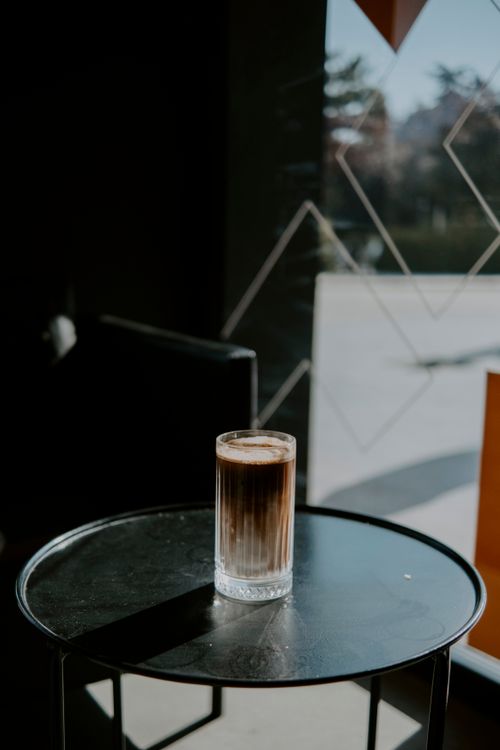 Free A artistic shot of a coffee glass on a table in a dark cafe with window reflections. Stock Photo