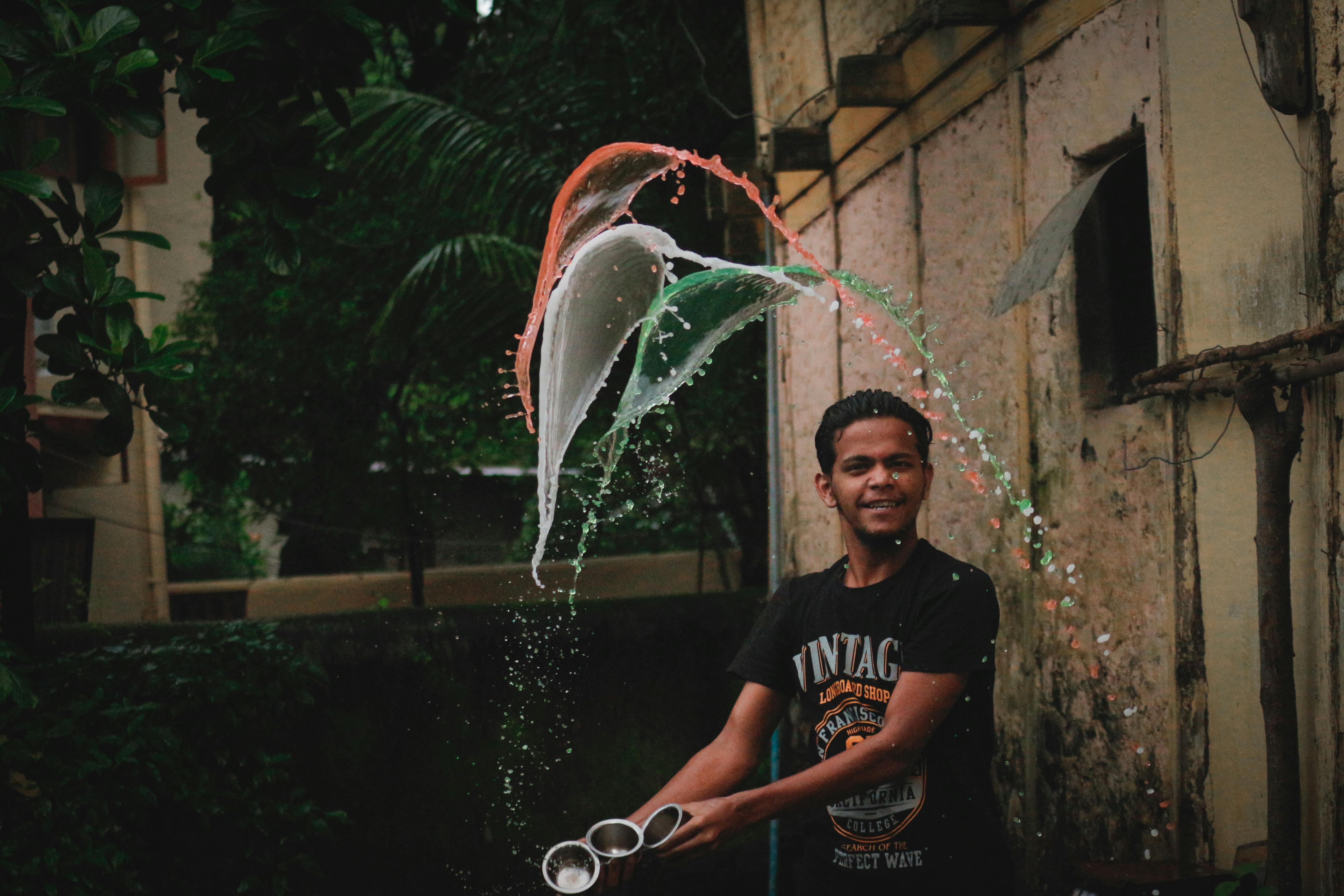 A young man skillfully tosses water, creating vibrant splash patterns in an urban outdoor setting.