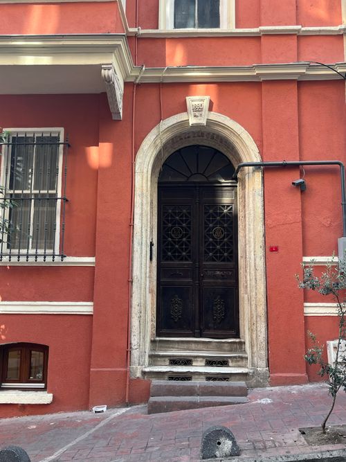 Free Capture of a red building facade with a vintage wooden door and arch, in an urban street setting. Stock Photo