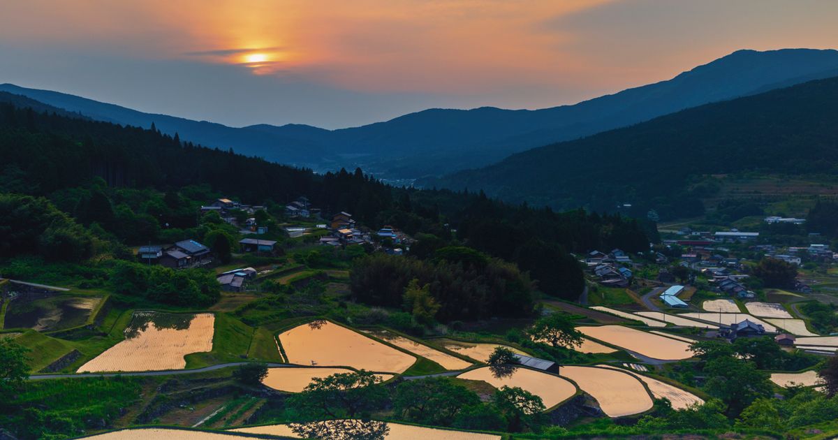 夕日に照らされる山あいの棚田と集落