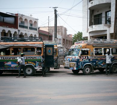 Colorful buses and people on a lively city street, showcasing vibrant urban life.
