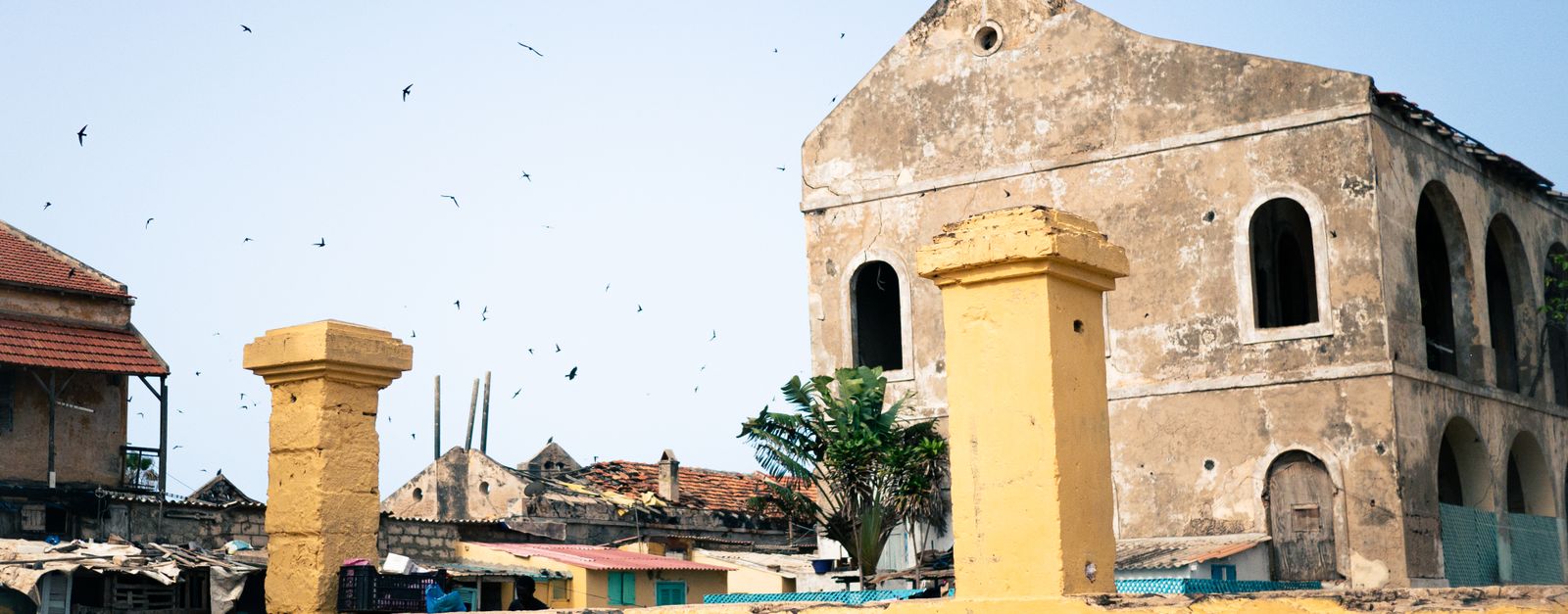 Vintage architecture with birds flying over a rustic townscape under clear skies.