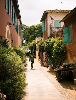 A person strolls through a vibrant urban alleyway with colorful buildings and lush greenery.