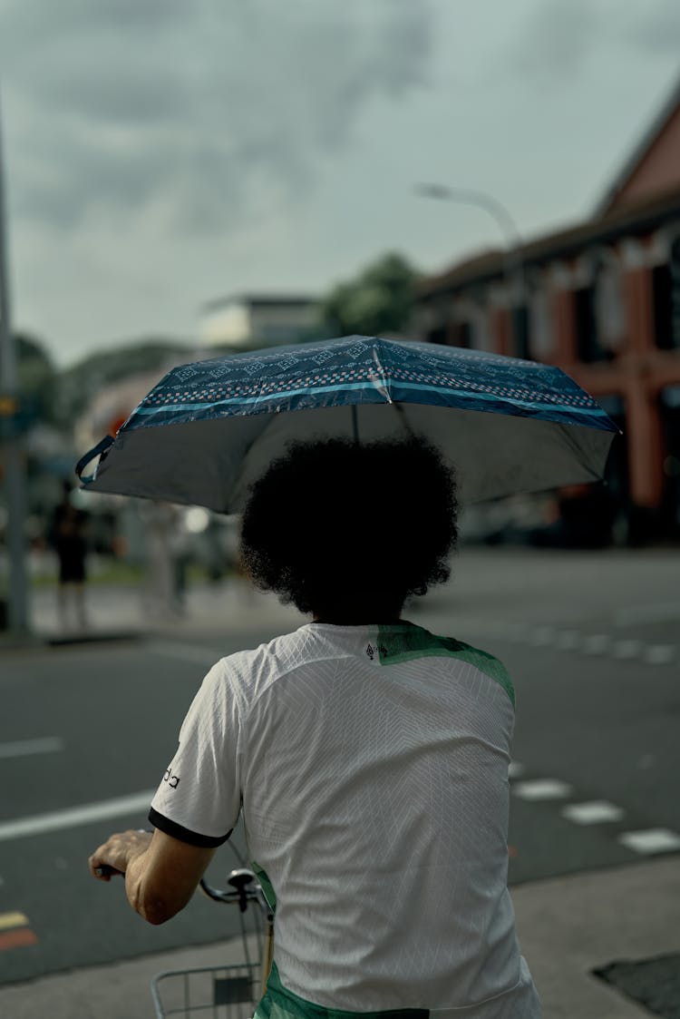 Man Riding Bike And Holding Open Umbrella