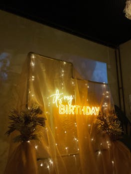 Stylish birthday backdrop with neon lights and draped fabric for party decor.