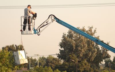 Worker operating an aerial lift bucket to reach high branches during tree work