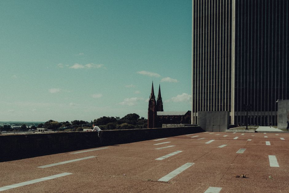 Wide view of a modern urban plaza with a cathedral spire in the background.