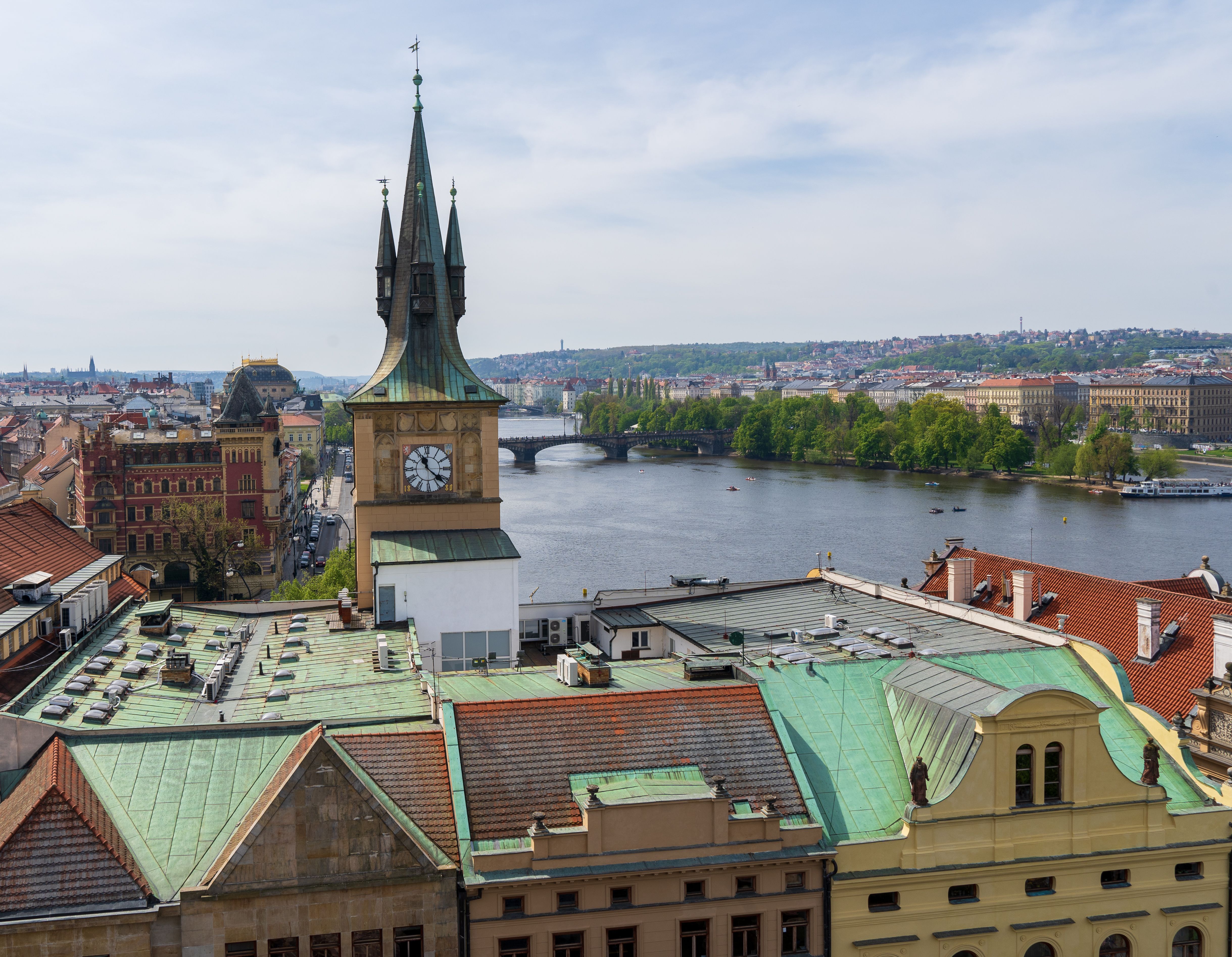 Aerial view of Prague cityscape featuring a historic clock tower by the Vltava River.