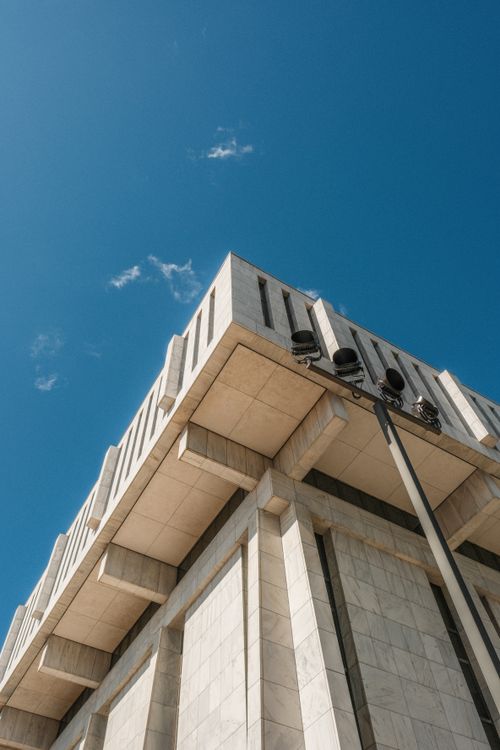 Free Low angle view of a modern concrete building with a clear blue sky and scattered clouds. Stock Photo