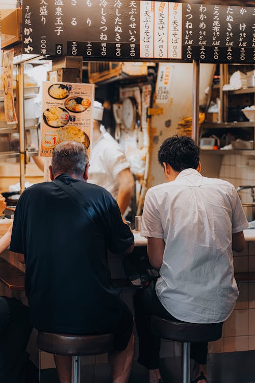 Men Sitting at Counter in Bar with Street Food