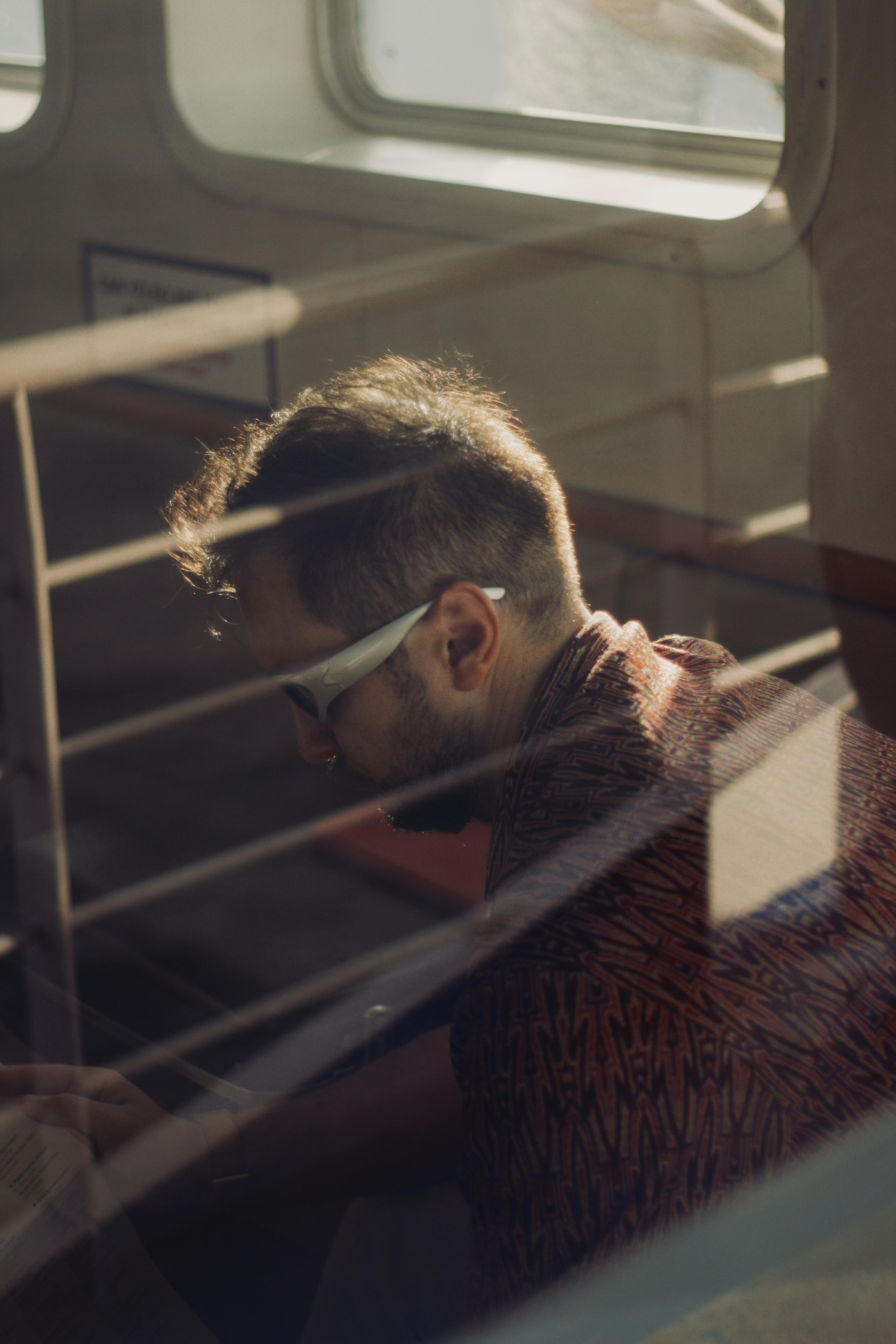 A man reading a book on an İstanbul ferry as sunlight filters through the window.