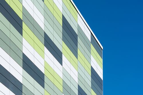 Free Colorful geometric facade of a modern building contrasting with a clear blue sky. Stock Photo