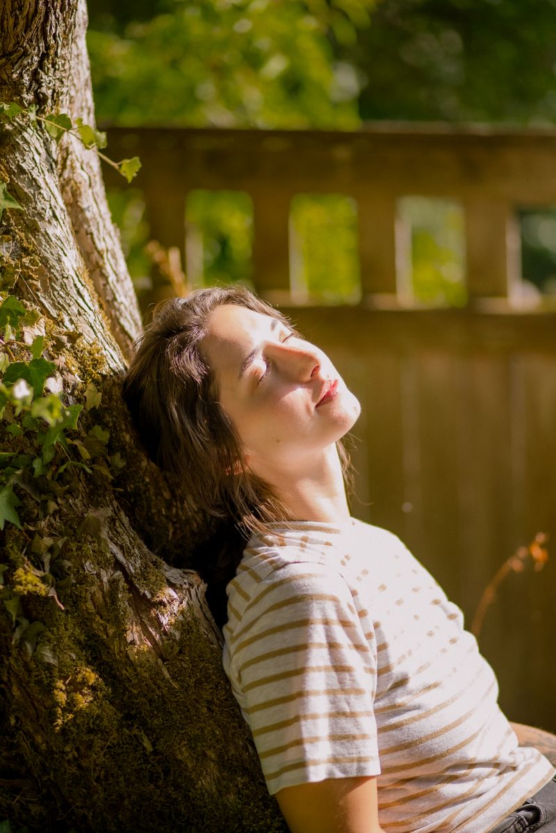 Woman sitting by a tree in sunlight