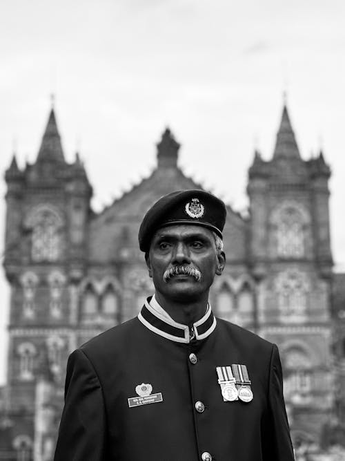 A Man in a Uniform Standing in front of a Historic Building 