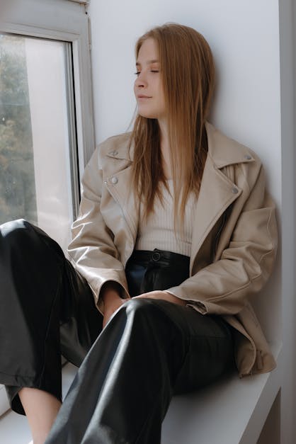 Model Wearing Beige Jacket and Black Leather Pants Sitting on the Window ·  Free Stock Photo