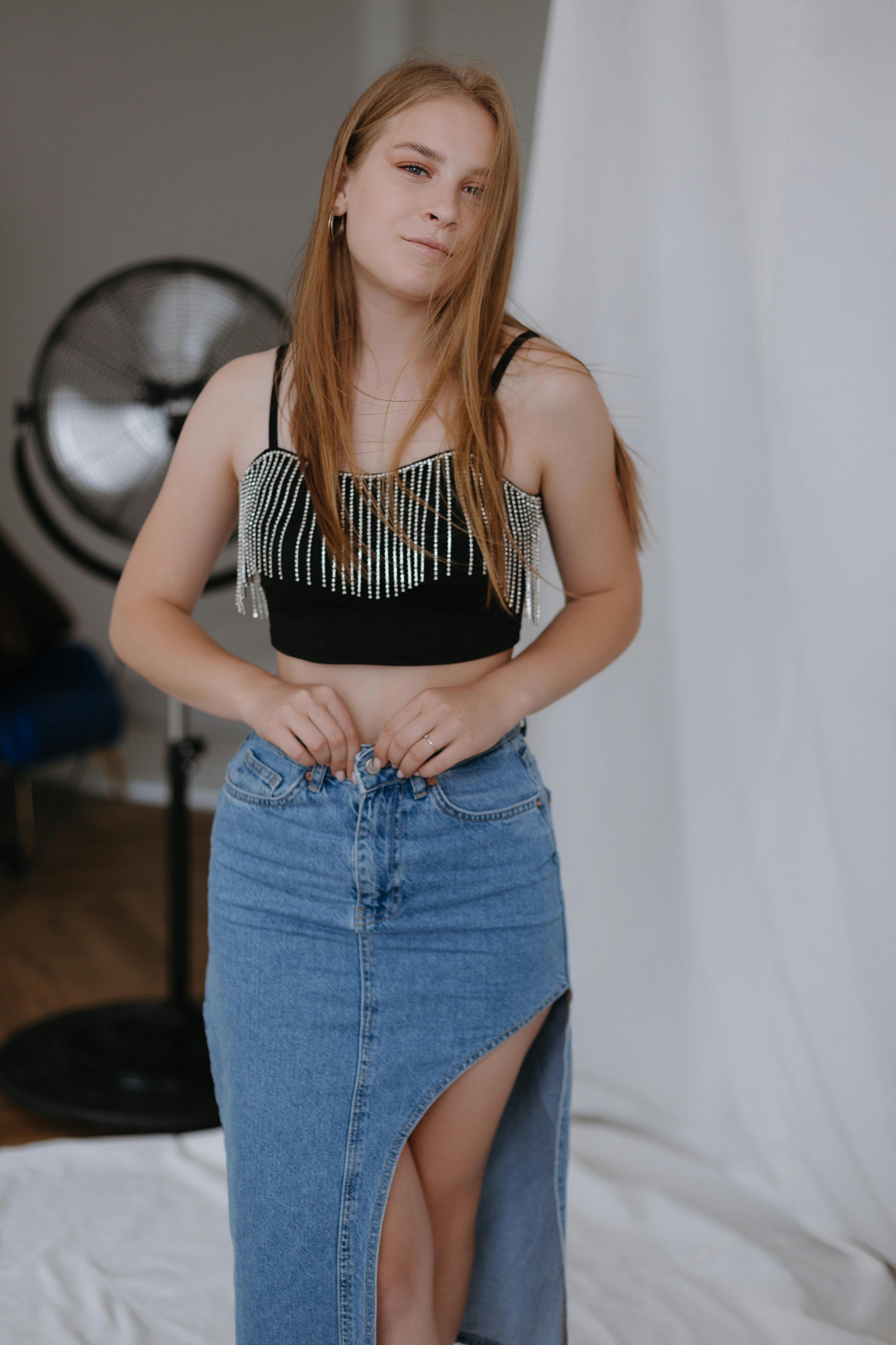 Young Blonde Woman in Blue Denim Skirt and Black Crop Top Sitting on a ...