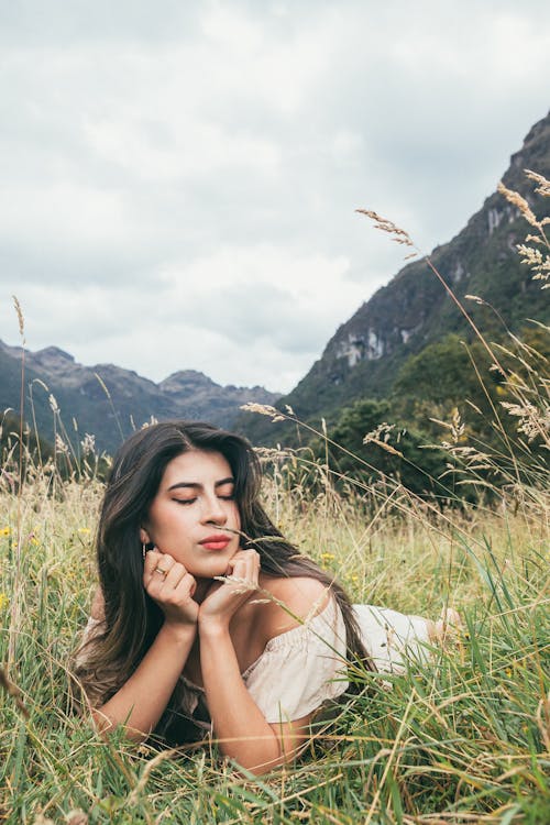 Free Brunette Woman Lying Down and Posing on Grassland Stock Photo