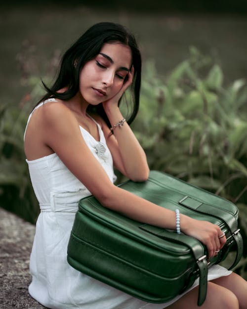 Woman in White Dress Holding Green Suitcase