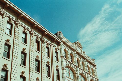 Free Elegant historical building facade set against a bright blue sky showcasing urban architectural beauty. Stock Photo