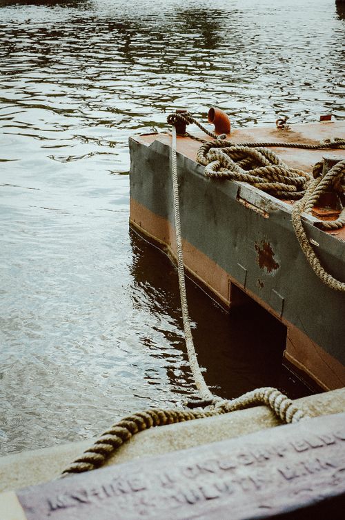Free A serene scene of a moored pier with ropes tying it down on calm water in daylight. Stock Photo