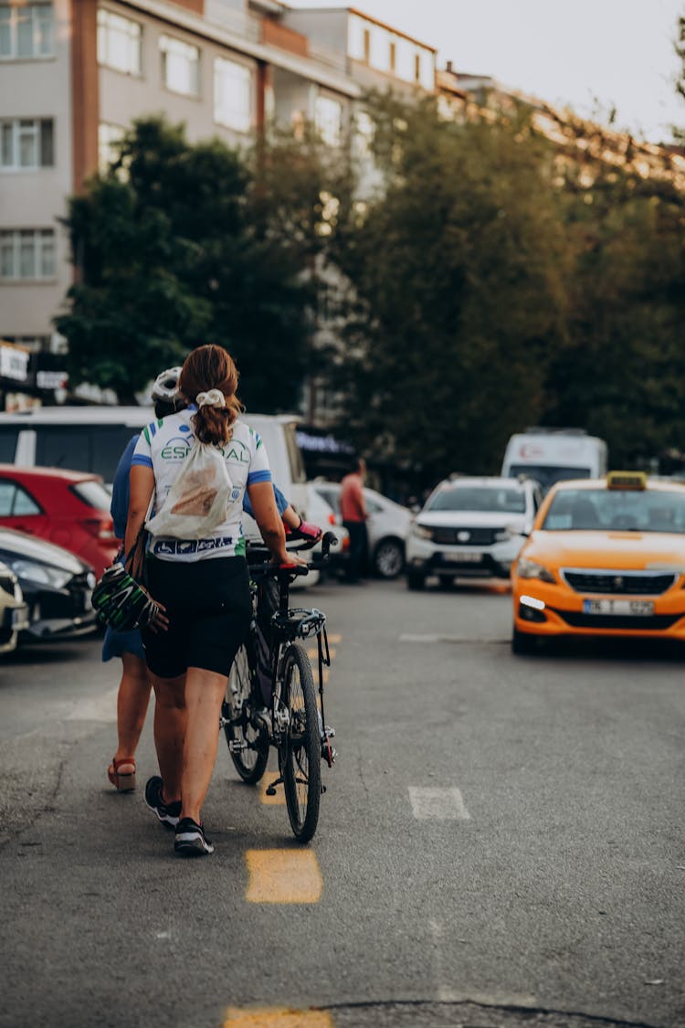 Women Walking On The Street And Pushing Bicycles 