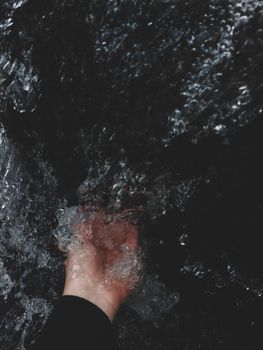 A close-up of a hand immersed in flowing water, showcasing the texture and movement.