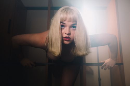 Free Surreal portrait of a blonde woman leaning into soft lighting, creating a dramatic effect. Stock Photo