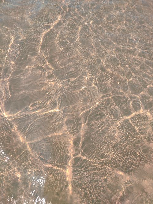 Free Close-up of rippling water with sunlight reflections, creating a textured surface. Stock Photo