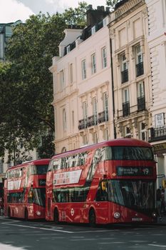 Iconic red double decker buses driving through the streets of London, showcasing the city's urban landscape and classic architecture.