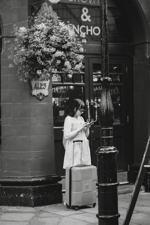 Woman Standing with Suitcase by Building Wall