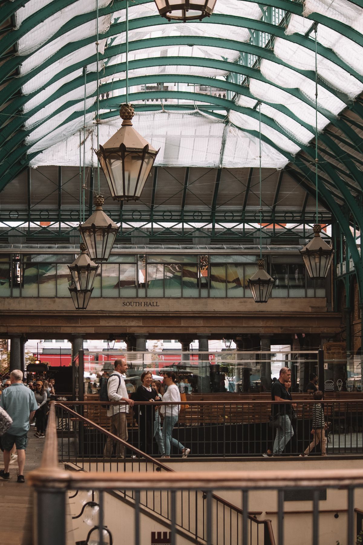 Shoppers and diners under Covent Garden Market's glass roof arcade