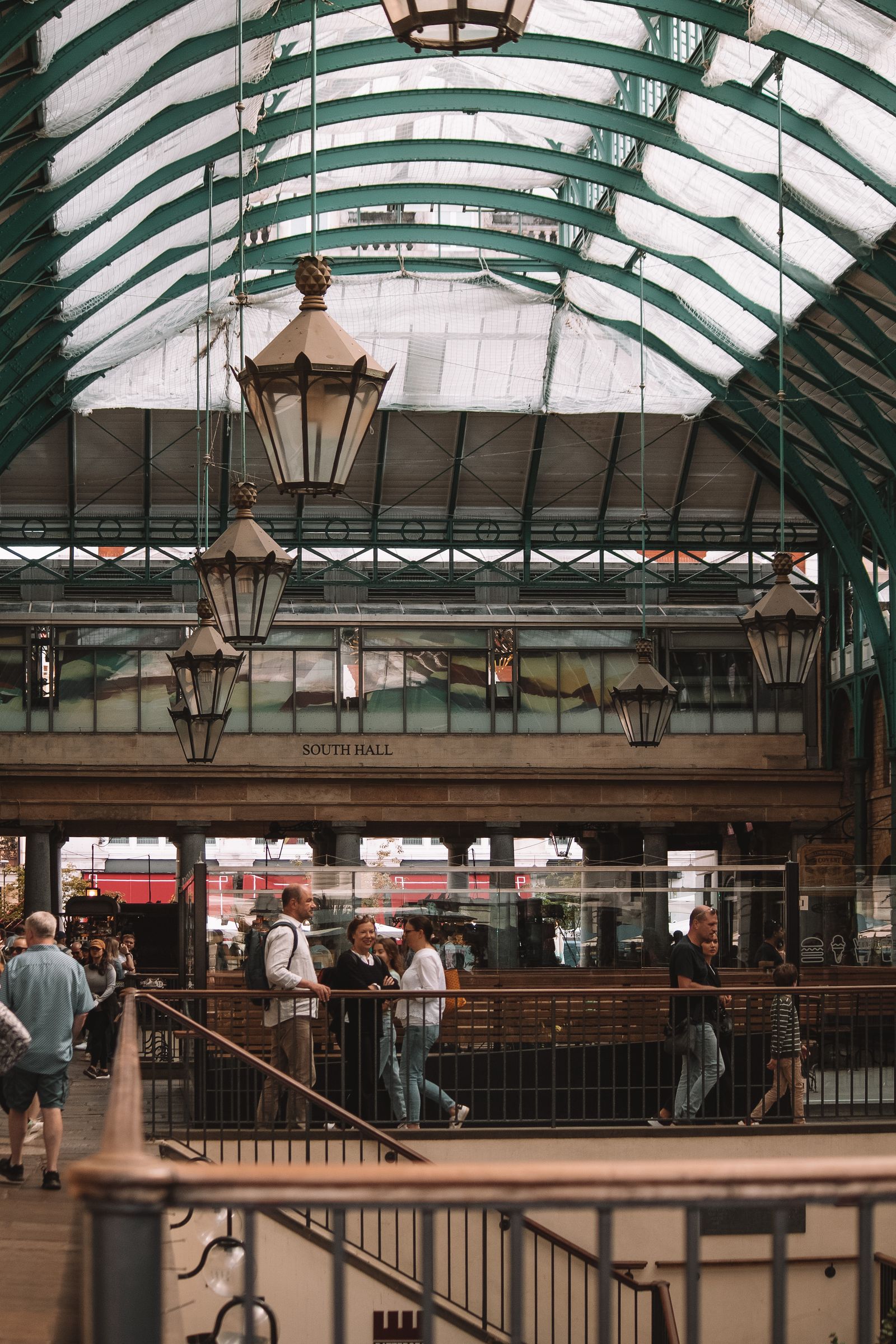 Shoppers and diners under Covent Garden Market's glass roof arcade