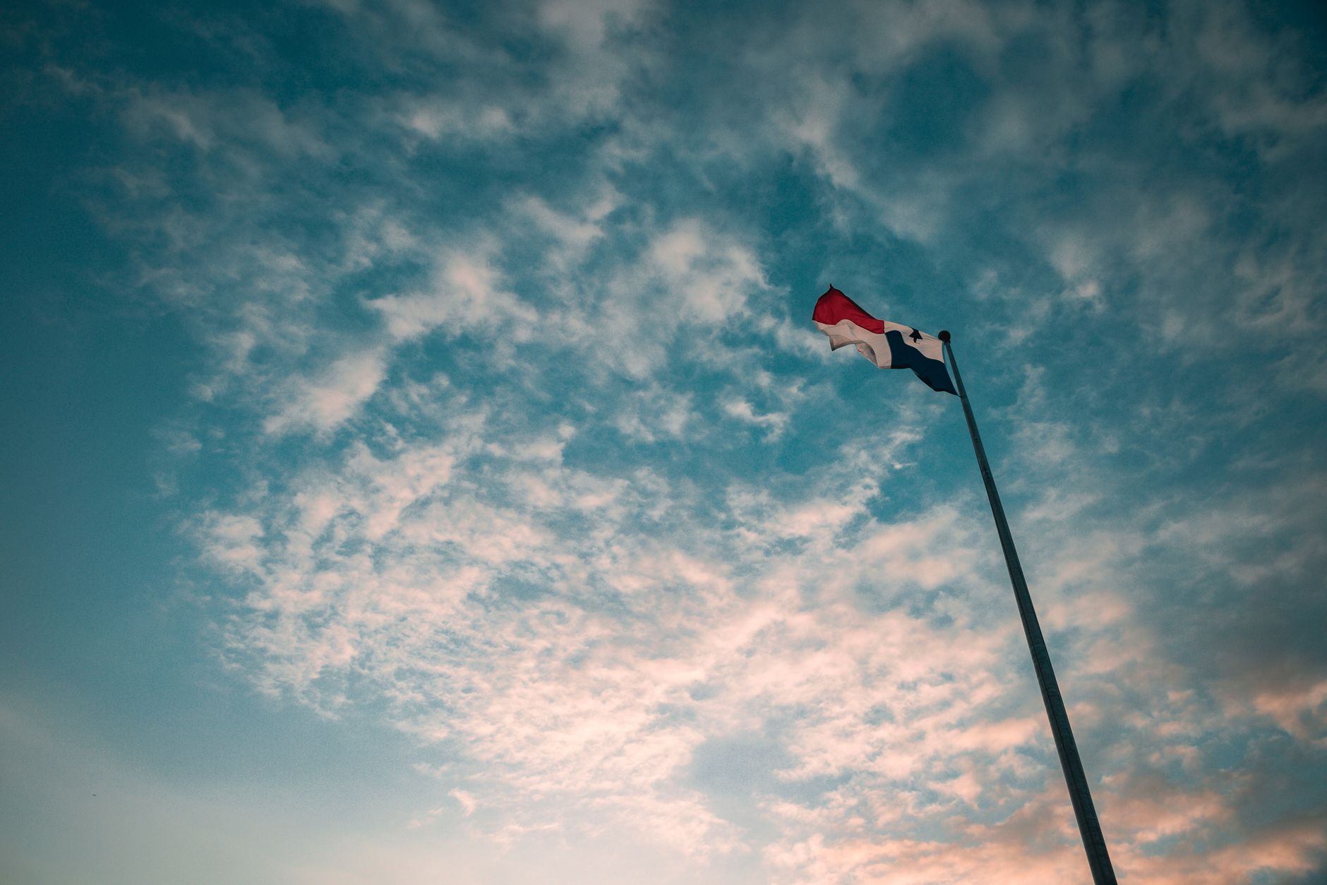 Panamanian flag on flagpole with clouds in background, low angle view in Panama City.