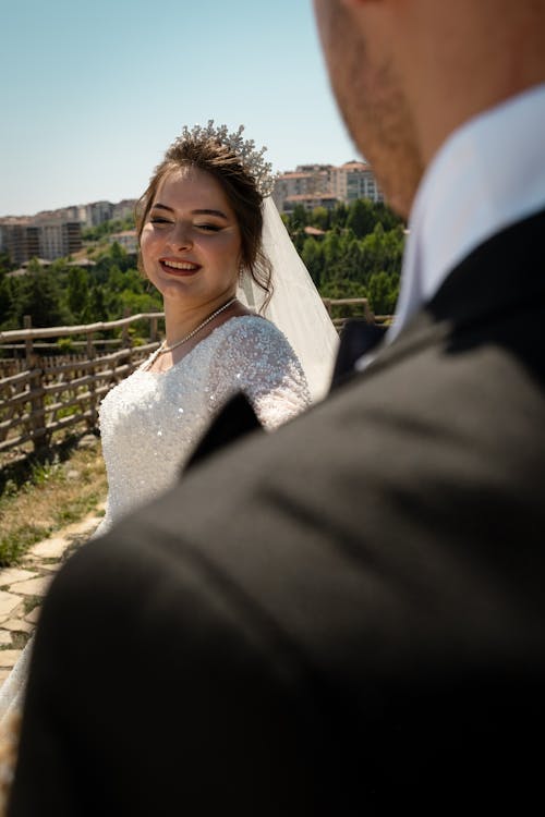 Woman in Wedding Dress Standing behind Man in Suit