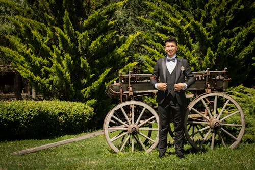 Smiling Groom in Suit Standing by Wooden Cart