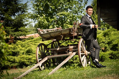 Smiling Groom Posing by Wooden Cart