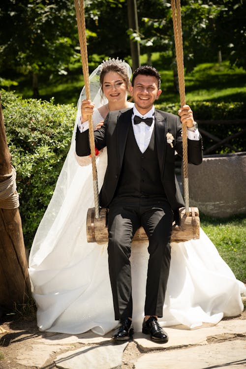 Smiling Newlyweds Posing on Wooden Swing