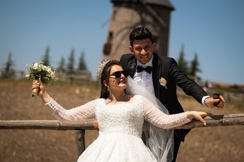 Smiling Newlyweds Standing by Wooden Railing
