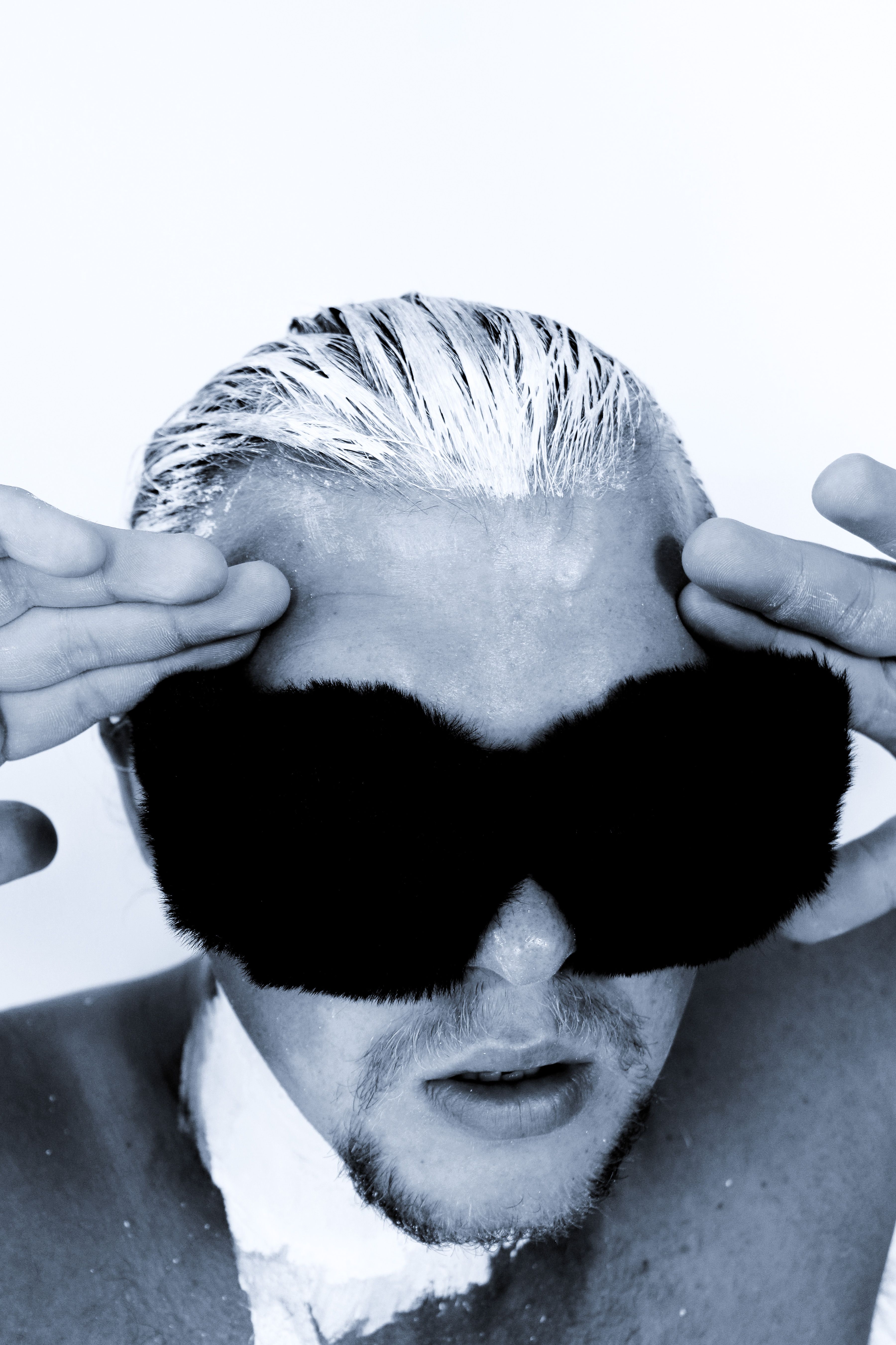 Creative portrait of a person with white-dyed hair and black fur mask, showcasing unique style.