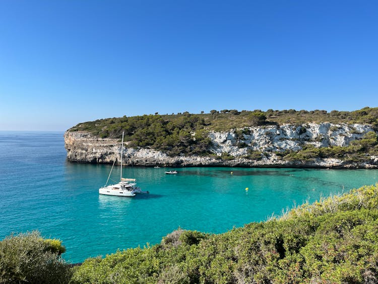 A Sailboat Near The Shore Under Blue Sky 