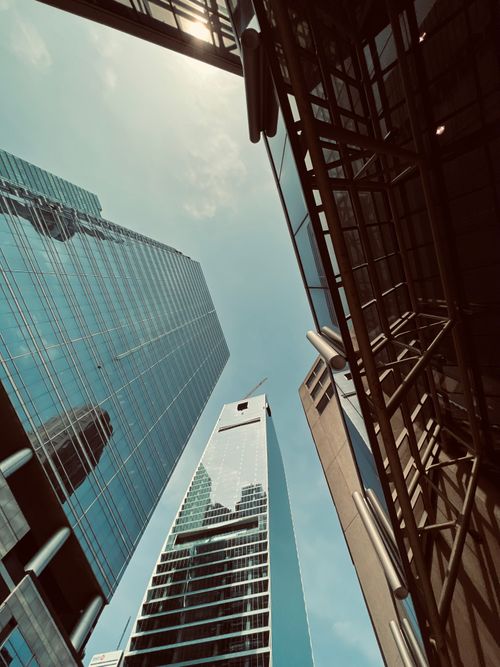 Free Dynamic low-angle view of urban skyscrapers against a clear blue sky. Stock Photo