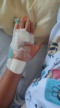 A child's hand with an IV line and bandages, symbolizing healthcare and patient care in a hospital setting.