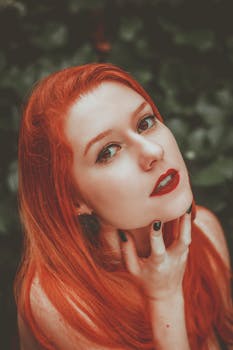 Captivating portrait of a redhead woman with striking makeup and pose, showcasing elegance.