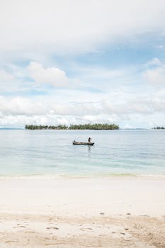 Serene beach scene with a solitary canoe and distant island view.