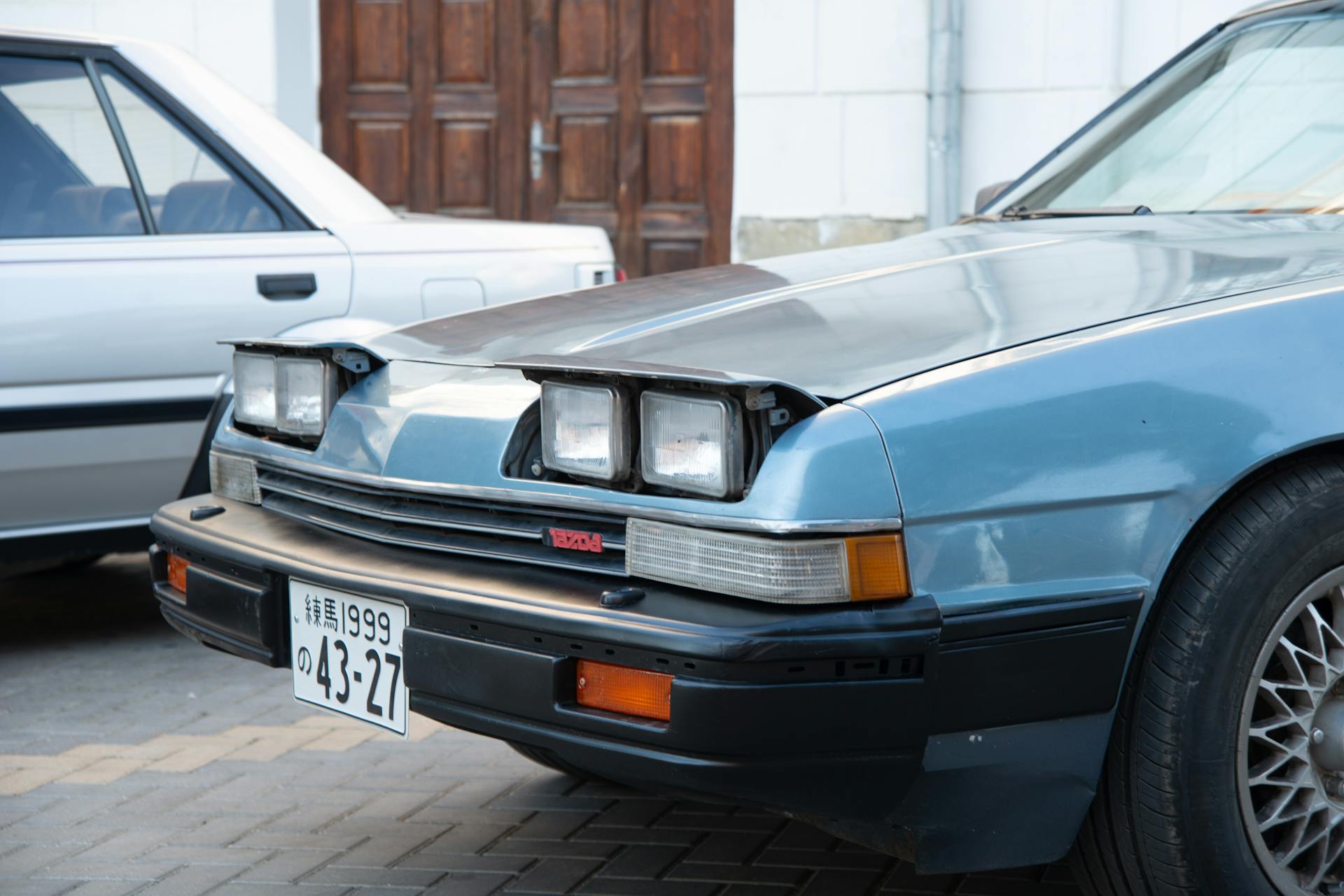 Close-up of a vintage Mazda coupe parked in an urban area, showcasing its classic design.