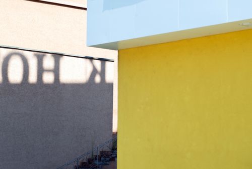 Free Captivating urban architectural scene with geometric shadows and a vibrant yellow wall. Stock Photo